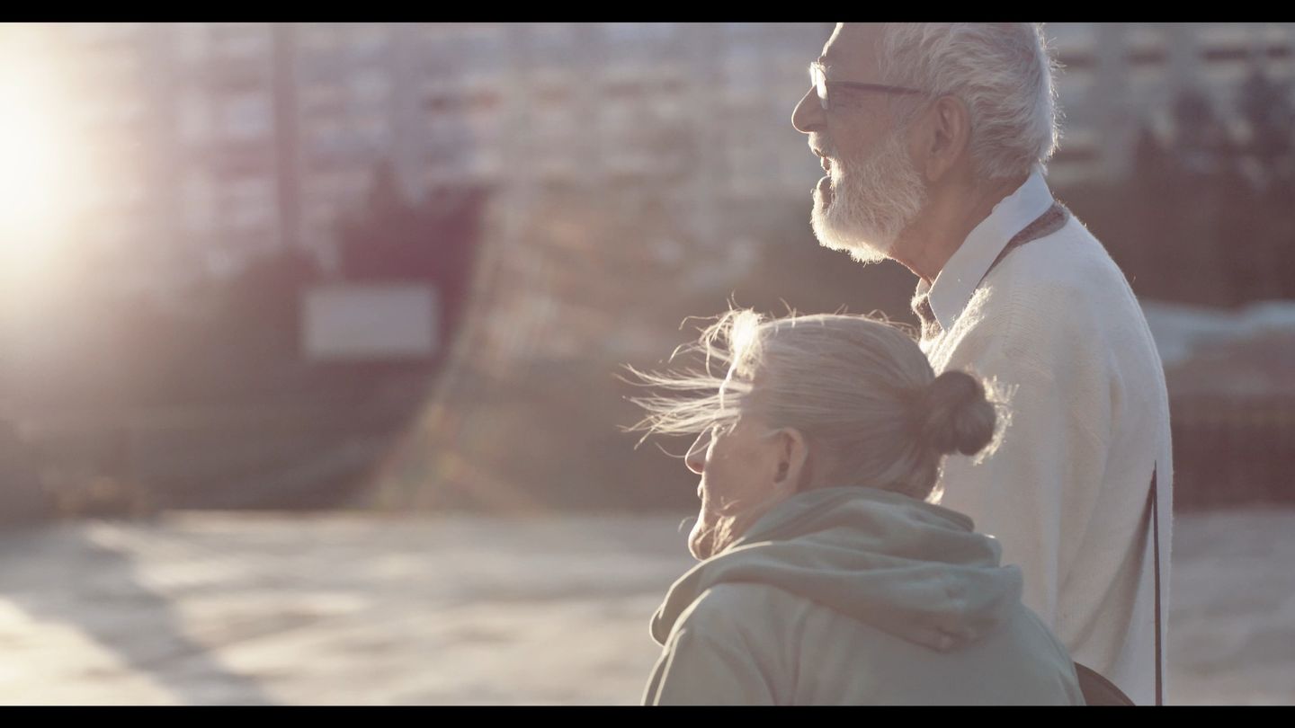 La pareja camina a contraluz, envuelta en una bruma de sol.