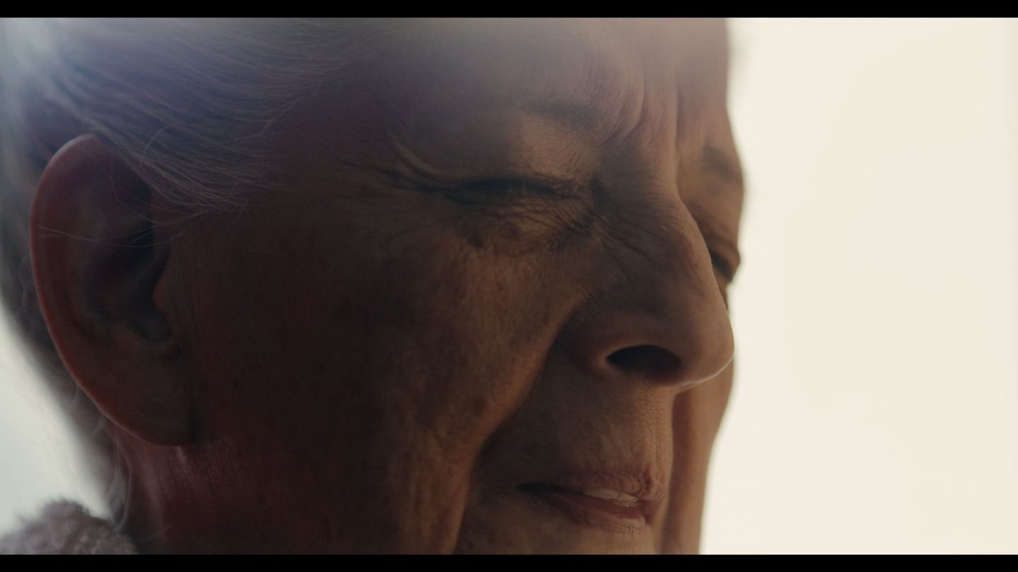 Primerísimo plano del rostro de una mujer mayor bañado en luz suave.