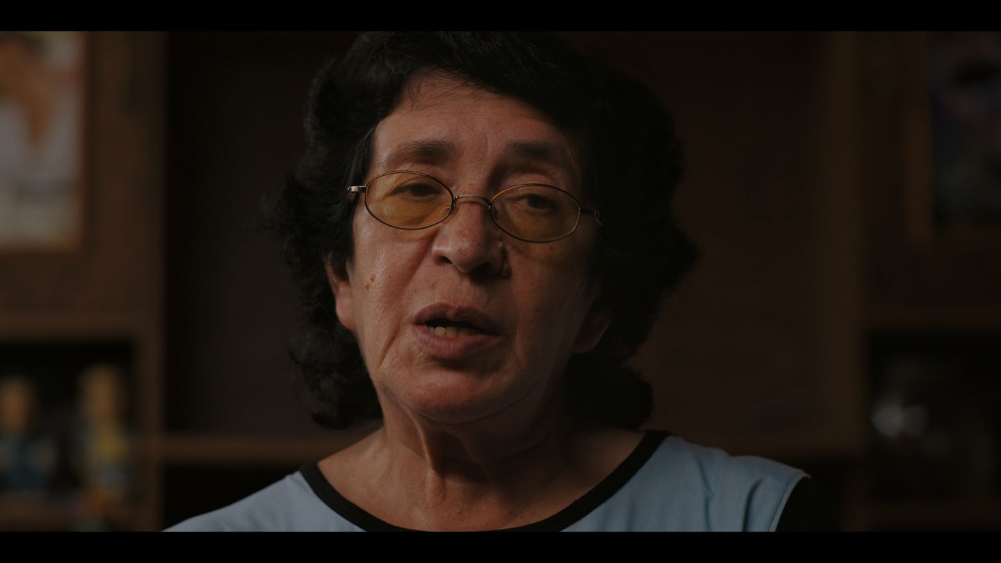 Retrato de una mujer con lentes y camiseta oscura, mirando a cámara.